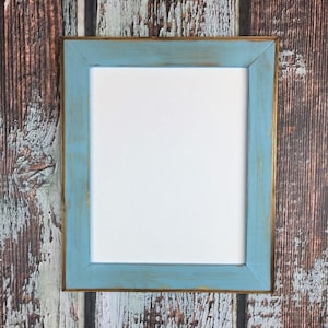 May include: A light blue picture frame with a distressed finish and a gold trim. The frame is empty and ready for a photo or artwork.