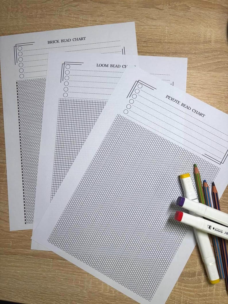 Puede incluir: Tres hojas de papel blanco con gr&aacute;ficos de cuentas, etiquetadas como "BRICK BEAD CHART", "LOOM BEAD CHART" y "PEYOTE BEAD CHART", est&aacute;n dispuestas sobre una superficie de madera. L&aacute;pices de colores y rotuladores con tapas rojas, moradas y amarillas est&aacute;n al lado.