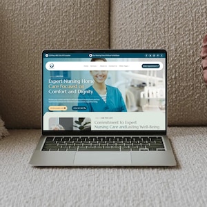 May include: A silver laptop displaying a website for an expert nursing home. The website's homepage features a smiling healthcare worker and the text "Expert Nursing Home Care Focused on Comfort and Dignity."