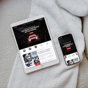 May include: A white tablet and a black smartphone displaying a website for auto repair and maintenance. The website features a red car graphic and the text "Auto Repair & Maintenance Get Free Estimate". The tablet and phone are on a white, textured surface.