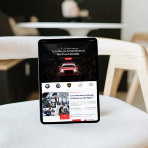 May include: A tablet displaying a website for New York Auto Repair. The site features a red car graphic, the text "Auto Repair & Maintenance," and the phrase "Get Free Estimate." Below are logos of car brands and images of mechanics.