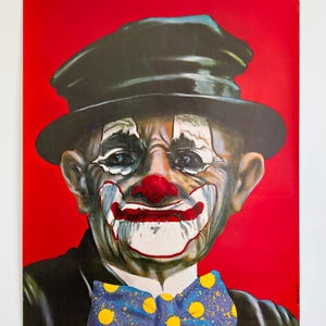 May include: A vintage clown poster against a red backdrop. The clown features a painted white face, red nose, and a blue bow tie with yellow polka dots. He wears a black hat and suit. The poster is a portrait.