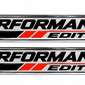 Op de afbeelding: Twee rechthoekige auto-emblemen met een chromen rand. De tekst PERFORMANCE is in het zwart en het woord EDITION is in het rood. Een zwarte streep en twee rode verticale balken bevinden zich tussen de woorden op een witte achtergrond.
