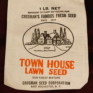 May include: A white paper bag with black and orange text. The bag is for Town House Lawn Seed, a product of Crosman Seed Corporation, East Rochester, NY. The bag says "1 lb. net" and "Sufficient to plant 250 square feet". It also says "Crosman's Famous Fresh Seed since 1838". The bag has a black and white illustration of a house with trees and a small pond.