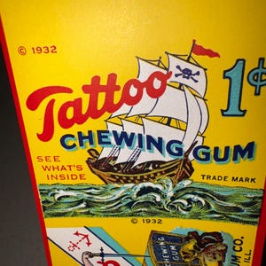 May include: Vintage "Tattoo Chewing Gum" packaging. The yellow background features a pirate ship illustration with a skull and crossbones flag, the text "Tattoo Chewing Gum", and the price "1&cent;". Includes the text "See What's Inside" and "Trade Mark".
