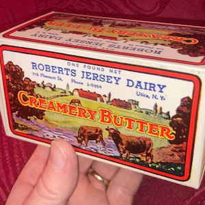 May include: A vintage Roberts Jersey Dairy Creamery Butter box. The box features a colorful illustration of cows grazing in a field, with the text "Creamery Butter" in a bold font. The box is labeled "One Pound Net".