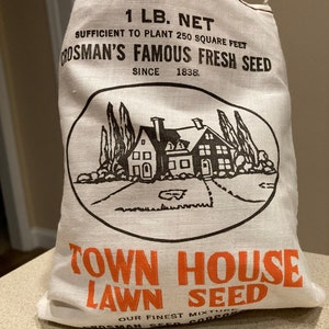 May include: A white burlap bag with black and orange text that reads "1 LB. NET", "SUFFICIENT TO PLANT 250 SQUARE FEET", "CROSMAN'S FAMOUS FRESH SEED", "SINCE 1838", "TOWN HOUSE", "LAWN SEED", "OUR FINEST MIXTURE", and "CROSMAN SEED CORP.". The bag features a black and white illustration of a house with a lawn.