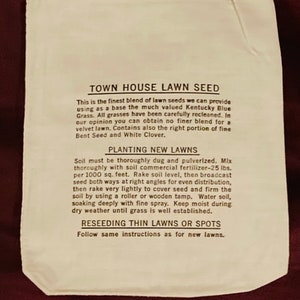May include: A white paper bag with black text that reads "Town House Lawn Seed". The bag contains instructions for planting new lawns and reseeding thin lawns or spots. The instructions include using 25 pounds of fertilizer per 1000 square feet.