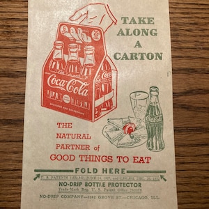 May include: A brown paper bag with a red and white Coca-Cola carton illustration. The bag has green text that reads "Take Along A Carton" and "The Natural Partner of Good Things To Eat". The bag also has a green fold line with the text "Fold Here" and the text "NO-DRIP BOTTLE PROTECTOR" with the company name and address.