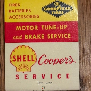 May include: A vintage matchbook with a yellow, red, and cream color scheme. The top section features "TIRES, BATTERIES, ACCESSORIES" and a "Goodyear Tires" logo. The middle section reads "MOTOR TUNE-UP and BRAKE SERVICE." The bottom has a "Shell" logo and "Cooper's SERVICE."