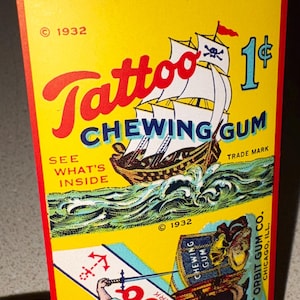May include: Vintage Tattoo Chewing Gum package from 1932. The yellow package features a pirate ship with a skull and crossbones flag, the text "Tattoo Chewing Gum", and the price of 1&cent;. The package also includes an illustration of a sailor.