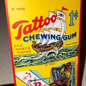 May include: Vintage Tattoo Chewing Gum package from 1932. The yellow package features a pirate ship with a skull and crossbones flag, waves, and the text "Tattoo Chewing Gum." The price is 1&cent;.