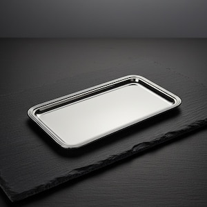 Puede incluir: Una bandeja rectangular de metal plateado con una superficie pulida y reflectante y un borde elevado de varias capas. La bandeja presenta esquinas redondeadas y una base plana y lisa, ofreciendo una estética metálica limpia y brillante.
