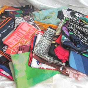 Puede incluir: Una colección de coloridas bufandas de seda con varios patrones y diseños. Las bufandas son en tonos de rojo, rosa, azul, verde y negro, con estampados florales, geométricos y abstractos. Algunas bufandas tienen la marca "Leonard" impresa.