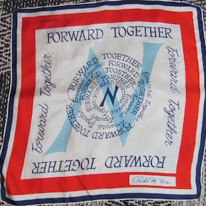 May include: Square silk scarf with a white background, red and blue borders, and the words "FORWARD TOGETHER" in navy blue. The center features a stylized "N" and the same phrase in a circular pattern. Signed "Rachel M. Nixon".