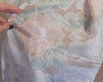 May include: A white, pink, and green floral print scarf with a sheer texture. The scarf is folded and draped over a mannequin.