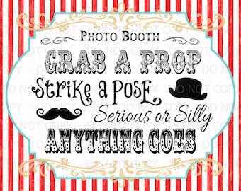 May include: A white sign with black text that reads "Photo Booth Grab a Prop Strike a Pose Serious or Silly Anything Goes". The sign has a red and white striped background and a gold and blue border.