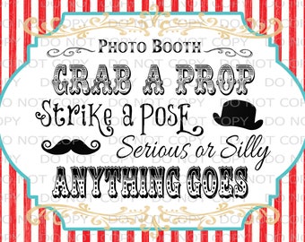 May include: A white sign with black text that says "Photo Booth Grab a Prop Strike a Pose Serious or Silly Anything Goes". The sign has a red and white striped background and a gold ornate border.
