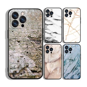 May include: A collection of phone cases with various designs. One case features a textured bark pattern, while others showcase marble-like patterns in white, gold, pink, and blue. Each case has a black border and a camera cutout.