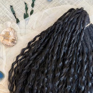 May include: A bundle of dark black hair extensions featuring a tight, wavy, and twisted texture. The strands are gathered together at the top with a light-colored string, showcasing a consistent dark color throughout the entire length of the hair.