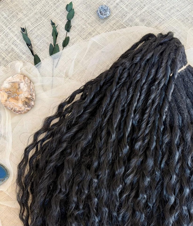May include: A bundle of dark black hair extensions featuring a tight, wavy, and twisted texture. The strands are gathered together at the top with a light-colored string, showcasing a consistent dark color throughout the entire length of the hair.