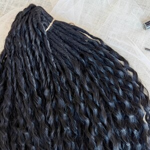 May include: A bundle of black synthetic hair extensions featuring a tight, twisted, and wavy texture. The strands are gathered at the top with a thin, light-colored cord, creating a uniform arrangement of long, dark, and voluminous hair pieces.