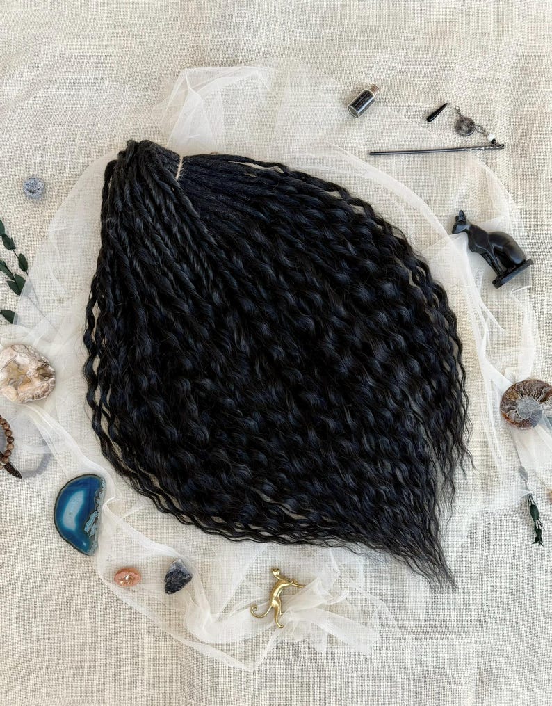 May include: A set of black synthetic hair extensions featuring a wavy, twisted texture. The hair is arranged in a fan shape, showcasing long, dark strands with a consistent curl pattern throughout the length of the hair pieces.