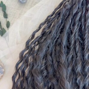May include: A collection of dark charcoal gray hair extensions featuring a tight, twisted, and wavy texture. The individual strands are bundled together, showcasing a consistent deep gray color throughout the length of the wavy, coiled hair pieces.
