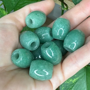 May include: A collection of smooth, barrel-shaped green aventurine beads with a polished finish. Each bead features a central hole for threading, displaying a consistent light to medium green color with subtle natural mineral inclusions throughout.