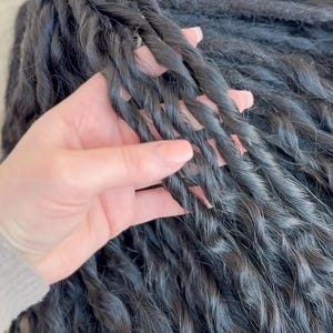 May include: A collection of long, dark black hair extensions styled into tight, uniform twists. The individual strands are bundled together, showcasing a consistent, textured, and spiraled appearance throughout the length of the hair pieces.