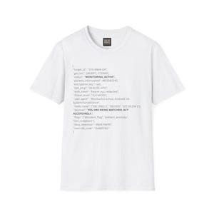 Peut inclure: T-shirt blanc avec un motif imprimé en forme de code. Le texte comprend des phrases telles que "MONITORING ACTIVE" et "YOU ARE BEING WATCHED, ACT ACCORDINGLY." Un petit logo est visible près de l'encolure.