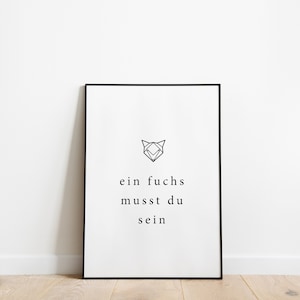 Könnte beinhalten: Ein gerahmter Druck mit schwarzem Rand, der an einer weißen Wand lehnt. Der Druck zeigt einen geometrischen Fuchskopf über dem deutschen Text "ein fuchs musst du sein" in minimalistischem Stil. Der Hintergrund ist weiß.