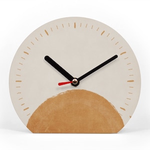 Könnte beinhalten: Eine cremefarbene, halbkreisförmige Tischuhr mit einem braunen, sonnenähnlichen Design am unteren Rand. Die Uhr hat schwarze Zeiger, einen roten Sekundenzeiger und braune Striche, die die Stunden markieren. Es ist ein dekorativer Einrichtungsgegenstand.