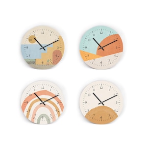 Könnte beinhalten: Vier runde Wanduhren mit abstrakten Designs in Pastellfarben. Jede Uhr hat ein weißes Zifferblatt mit schwarzen Zeigern und Zahlen. Die Designs umfassen geometrische Formen, einen Regenbogen und eine Sonne, für die Inneneinrichtung.