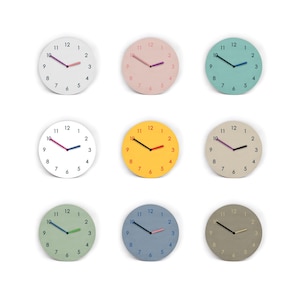 Könnte beinhalten: Eine Sammlung von neun runden Wanduhren, die in einem Raster angeordnet sind. Jede Uhr verfügt über ein einfarbiges Zifferblatt mit schwarzen Ziffern von 1 bis 12 und zwei kontrastfarbenen Zeigern. Die Farben umfassen Weiß, Rosa, Türkis, Gelb, Beige, Grün, Blau und Grau.