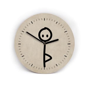 Könnte beinhalten: Runde Wanduhr mit beigem Zifferblatt und schwarzen Zeigern. Die Uhr zeigt eine schwarze Strichmännchenfigur in einer Yoga-Pose. Das Zifferblatt hat schwarze Striche, die die Stunden und Minuten markieren. Die Uhr ist ein dekorativer Artikel.