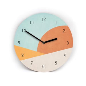 Könnte beinhalten: Eine runde Wanduhr mit minimalistischem Design. Das Zifferblatt ist in Abschnitte aus Hellblau, Orange, Creme und Gelb unterteilt. Schwarze Zeiger zeigen die Uhrzeit an, und schwarze Ziffern markieren die Stunden.