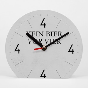 Könnte beinhalten: Eine hellgraue, halbkreisförmige Uhr mit schwarzen Ziffern an den Positionen 4, 8 und 12 Uhr. Die Zeiger sind schwarz, mit einem roten Sekundenzeiger. Der Text "KEIN BIER VOR VIER" ist schwarz gedruckt.