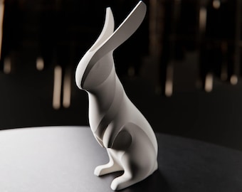 May include: A white, abstract rabbit sculpture with long, upright ears. The modern design features smooth, curved lines and a minimalist aesthetic. The sculpture is set against a dark background, highlighting its form.