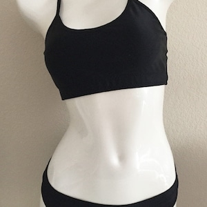 Peut inclure: Haut et bas de bikini noir avec des bretelles fines. Le haut a un col rond et le bas a une taille basse.