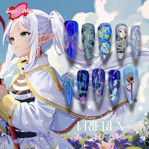 Könnte beinhalten: Eine Sammlung von zehn langen, mandelförmigen Acrylnägeln mit verschiedenen Designs. Die Nägel weisen Blau-, Grün- und Weißtöne auf, mit aufwendigen Kunstwerken, darunter Schmetterlinge, Blumen und Charaktere im Anime-Stil. Der Text "Sugar Nail" und "Long Stoned FRIEREN" sind sichtbar.