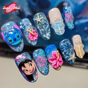 May include: A collection of custom acrylic nails with diverse designs. The nails display a blue Stitch character, pink hibiscus flowers, starfish, and water droplet effects. The text "Sugar Nail" is visible in the upper left corner.