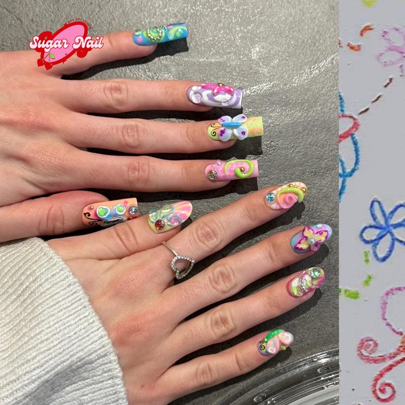May include: A close-up of a hand with long, decorated nails. Each nail features a unique design with bright colors, including butterflies, swirls, and gems. The nails are painted with a variety of colors, including pink, blue, green, and yellow. The image also includes the text "Sugar Nail".
