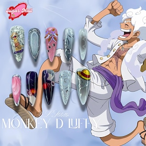 May include: A set of ten stiletto-shaped artificial nails with various designs. The nails feature cartoon character art, abstract patterns, and a straw hat design. The text "Sugar Nail" and "Monkey D Luffy" are visible.