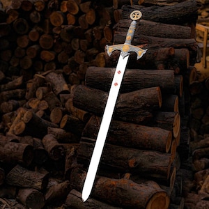 May include: A decorative sword with a silver blade and ornate gold and silver hilt. The hilt features a cross design, and the blade has three red crosses. The sword is leaning against a stack of brown logs.