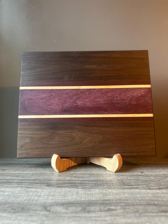 A genuinely handcrafted cutting board combining four exotic hardwoods — Purple Heart, Maple, Walnut & Padauk — creating a striking natural color mosaic that's functional art.