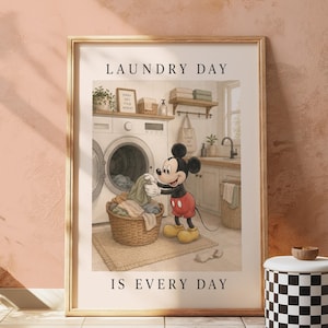 Può includere: Stampa artistica incorniciata con Topolino in una lavanderia. L'immagine mostra Topolino con il bucato, una lavatrice e un cesto della biancheria. Il testo recita "LAUNDRY DAY IS EVERY DAY". La cornice è dorata.