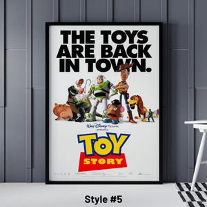 May include: A framed poster for the movie "Toy Story" featuring the film's characters. The poster has the text "THE TOYS ARE BACK IN TOWN" in large black letters. Below, the title "TOY STORY" is in yellow and red. Style #5 is written at the bottom.