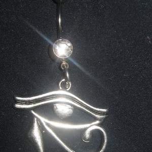 Puede incluir: Piercing corporal de plata con un cristal transparente y un dije de plata con forma de Ojo de Horus.