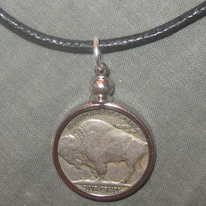 Op de afbeelding: Een zilveren ketting met een hanger met een buffalo nickel munt. De munt heeft de inscripties "United States of America" en "Five Cents".